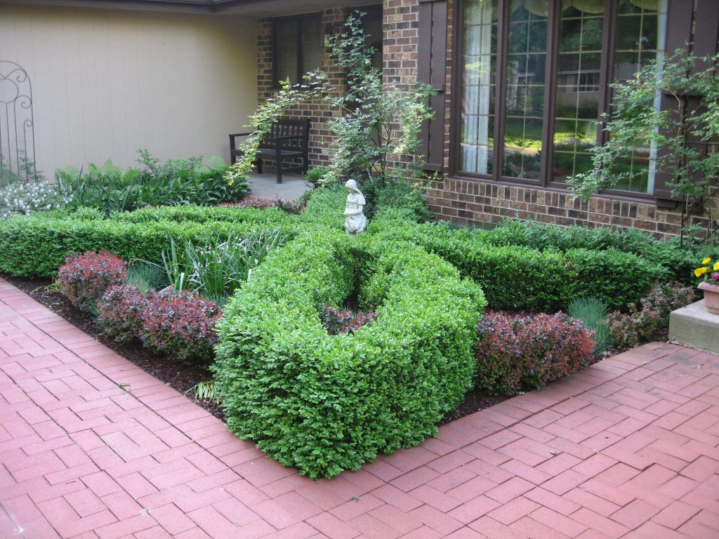 A small formal garden with hedges around a statue.