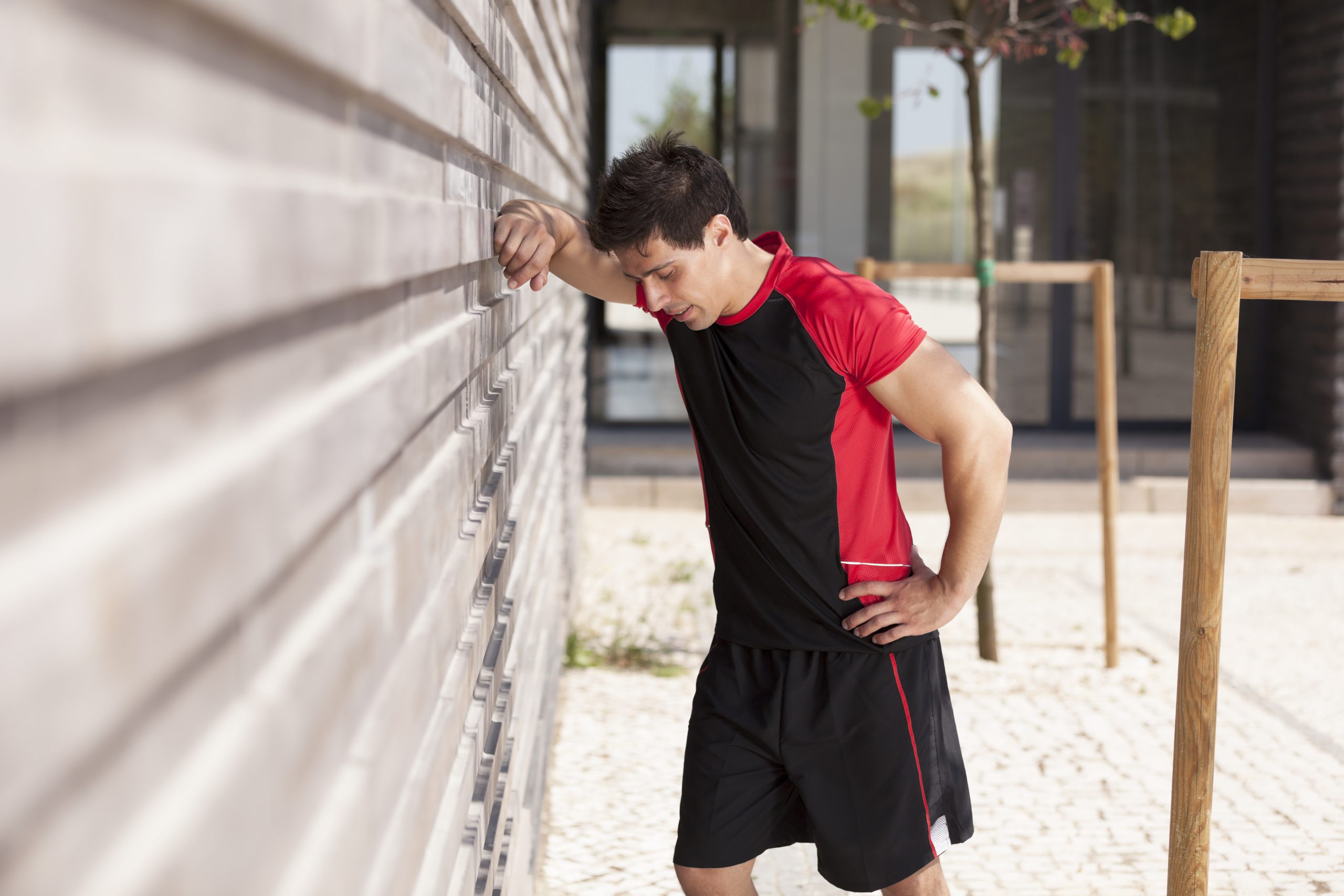 decorative: man leaning against a wall after a workout