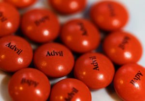 Red Advil pills are scattered on a white surface