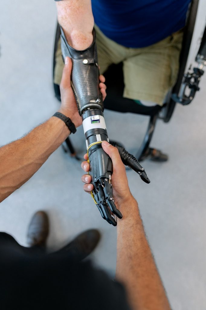 A man with a prosthetic arm is shaking another man's hand.
