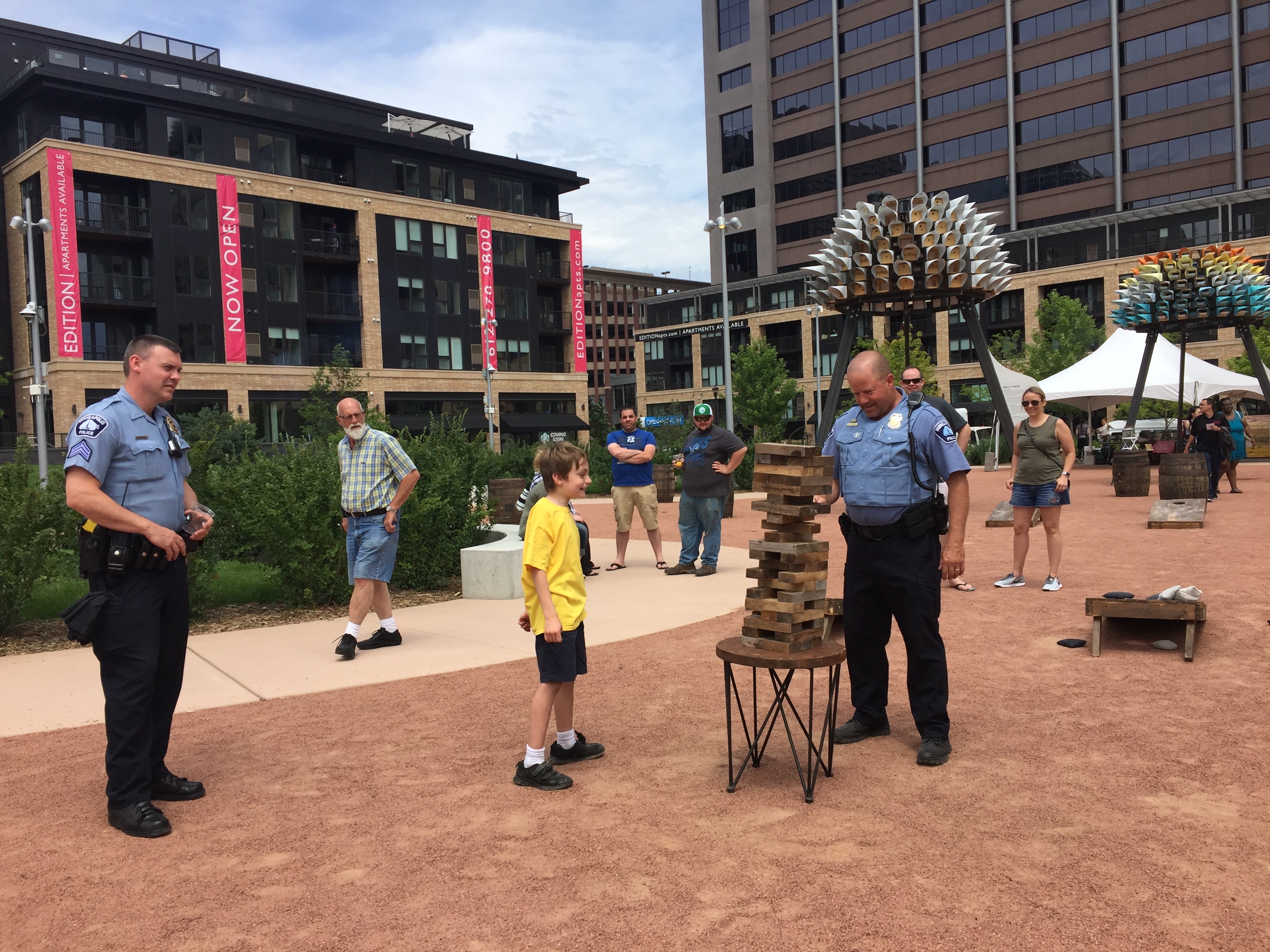 Picture of a police officer playing giant jenga with a boy in the Commons.