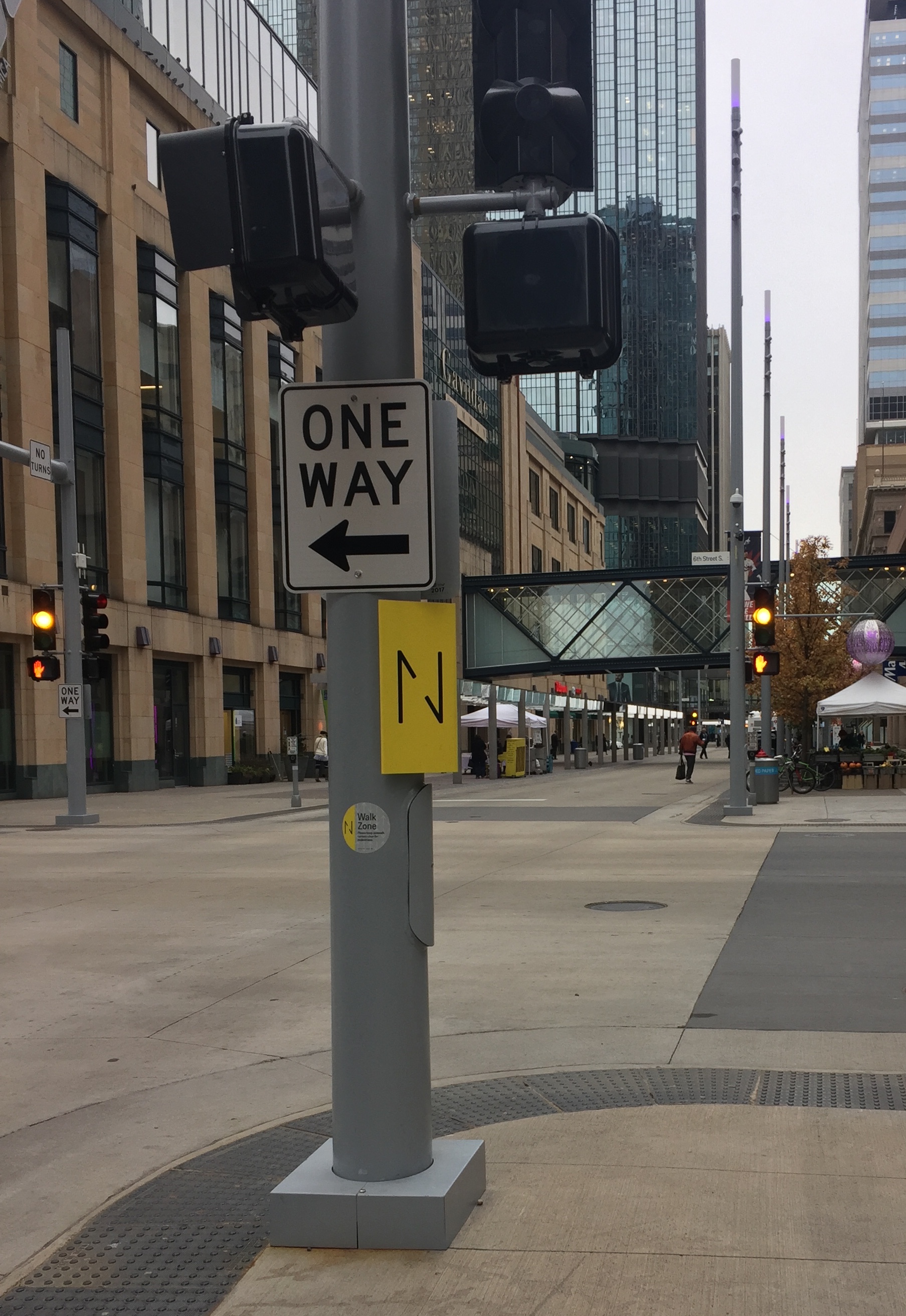 A gray pole with traffic signals, walk signs, and other signage on Nicollet Mall.