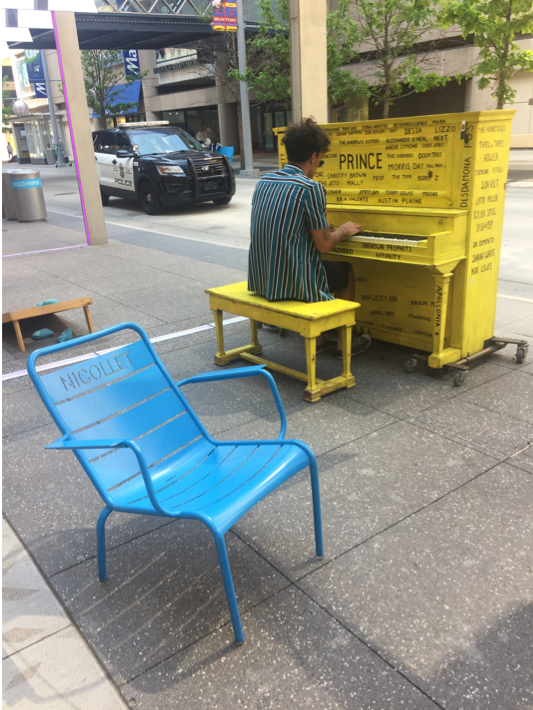 Picture of a yellow piano on Nicollet Mall with a person playing it.