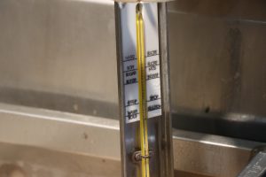 Syrup-making thermometer labeled with words instead of numbers. It is in an evaporator