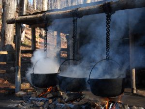 Three steaming black pots hung over a fire